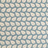 Detail of fabric in a repeating leaf print in cream on a blue field.