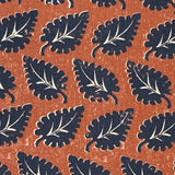 Detail of fabric in a repeating leaf print in navy and white on a rust field.