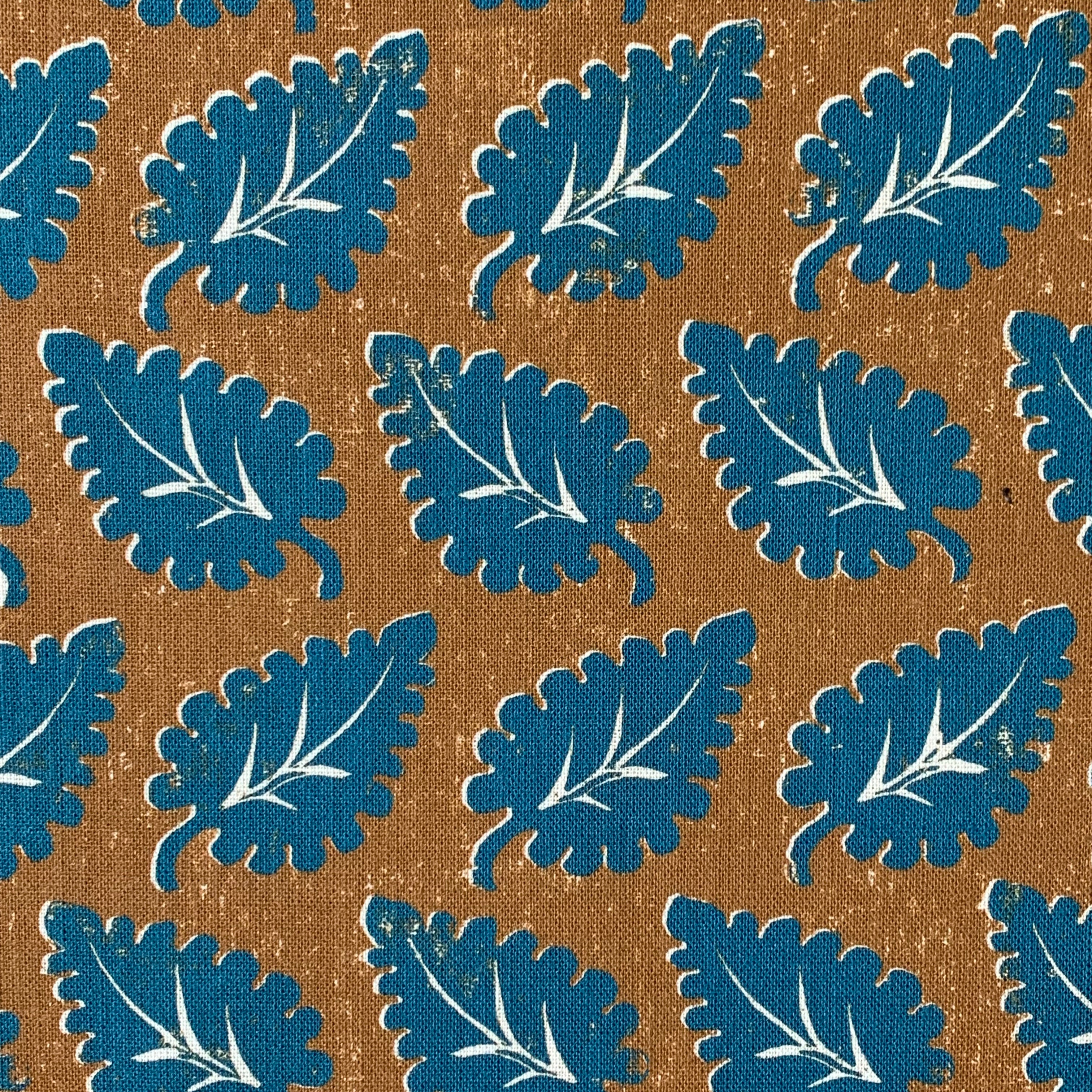Detail of a pattern with leaf silhouettes in turquoise against a brown field with accents of white.