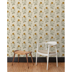 A chair and stool in front of a wall papered in a large-scale painterly floral print in mustard and green on a cream field.