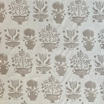 Detail of fabric in a repeating vase and plant print in tan on a white field.