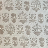 Detail of fabric in a repeating vase and plant print in tan on a white field.