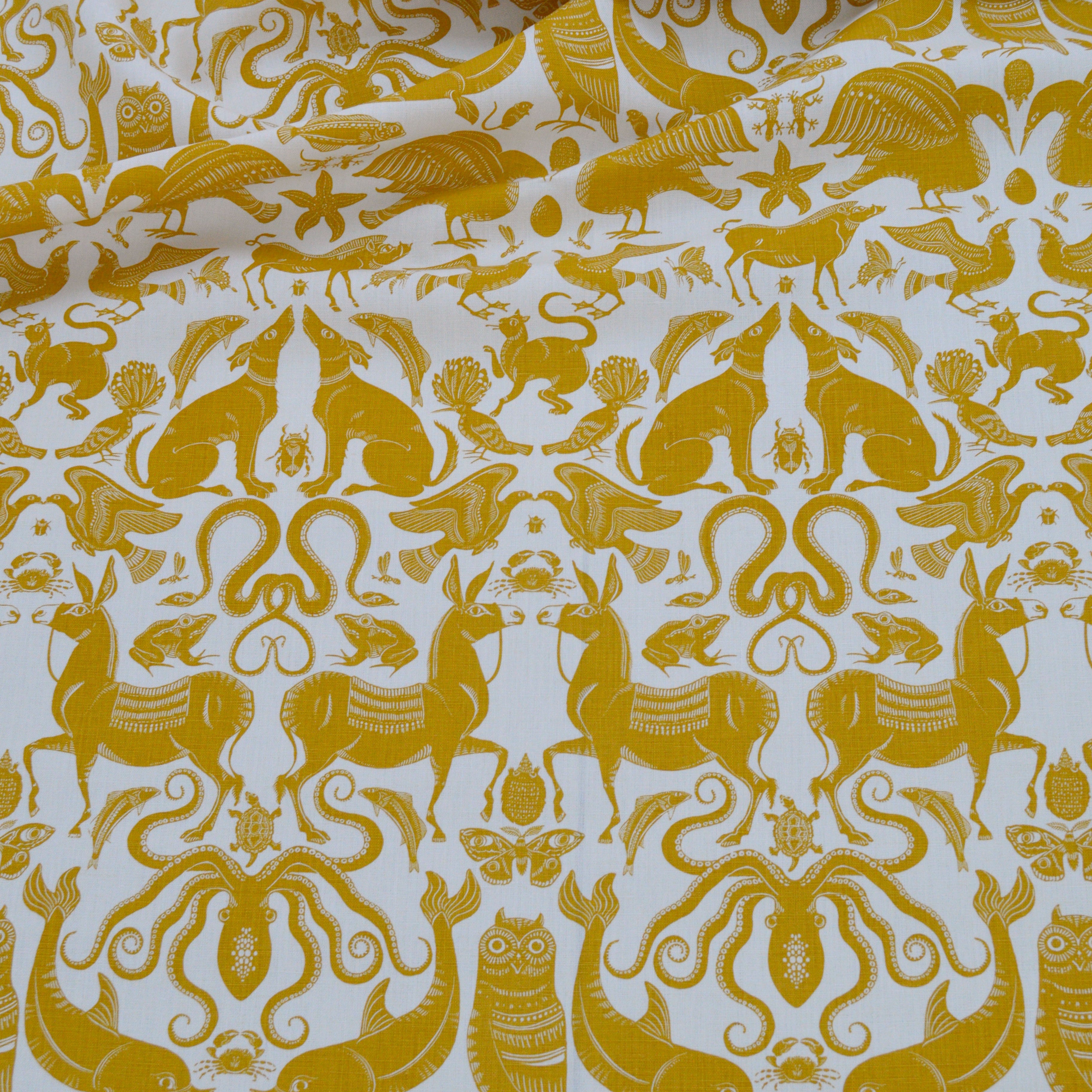 Draped patterned fabric with animals and sea creatures in yellow on a white background