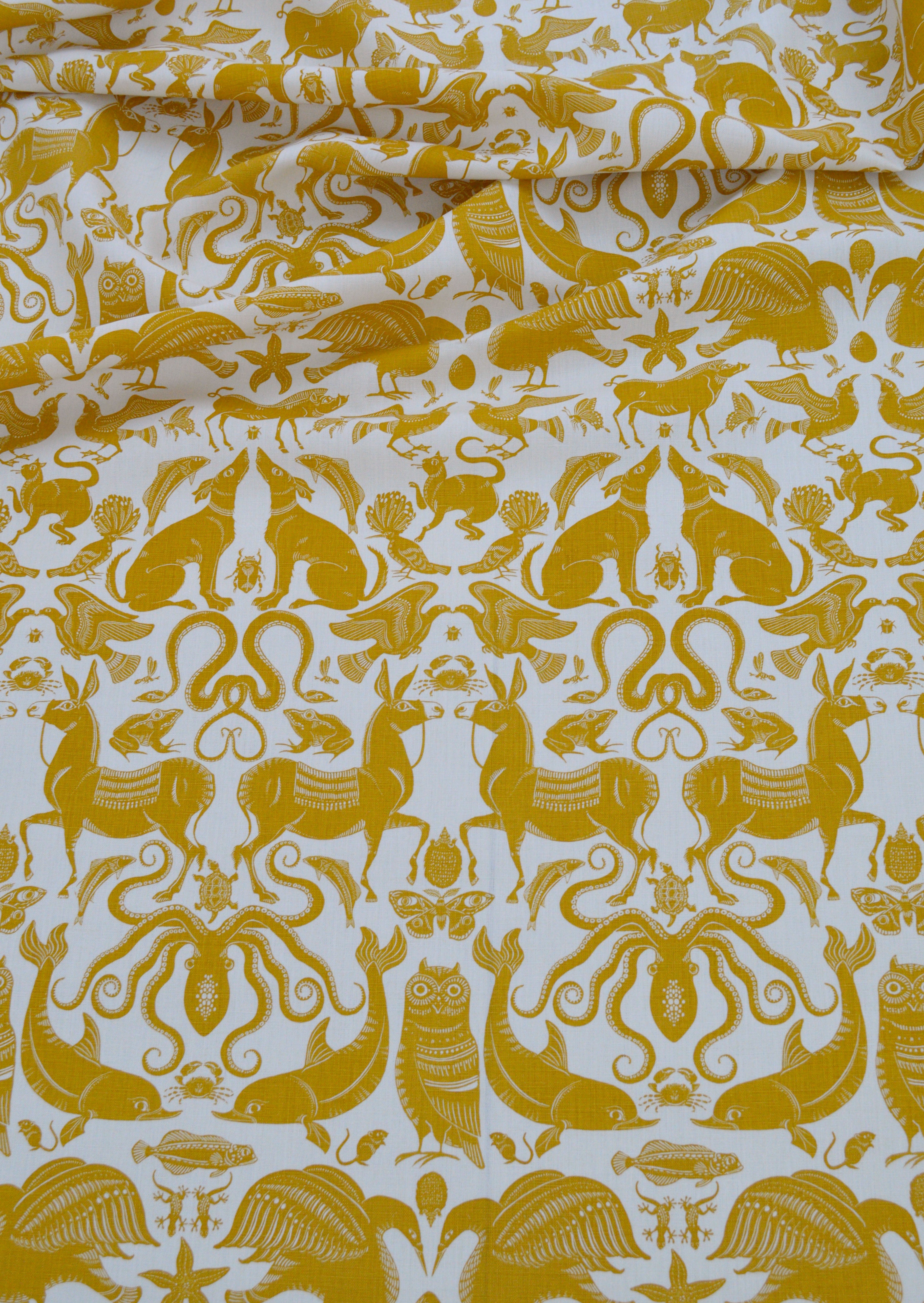 Draped patterned fabric with animals and sea creatures in yellow on a white background