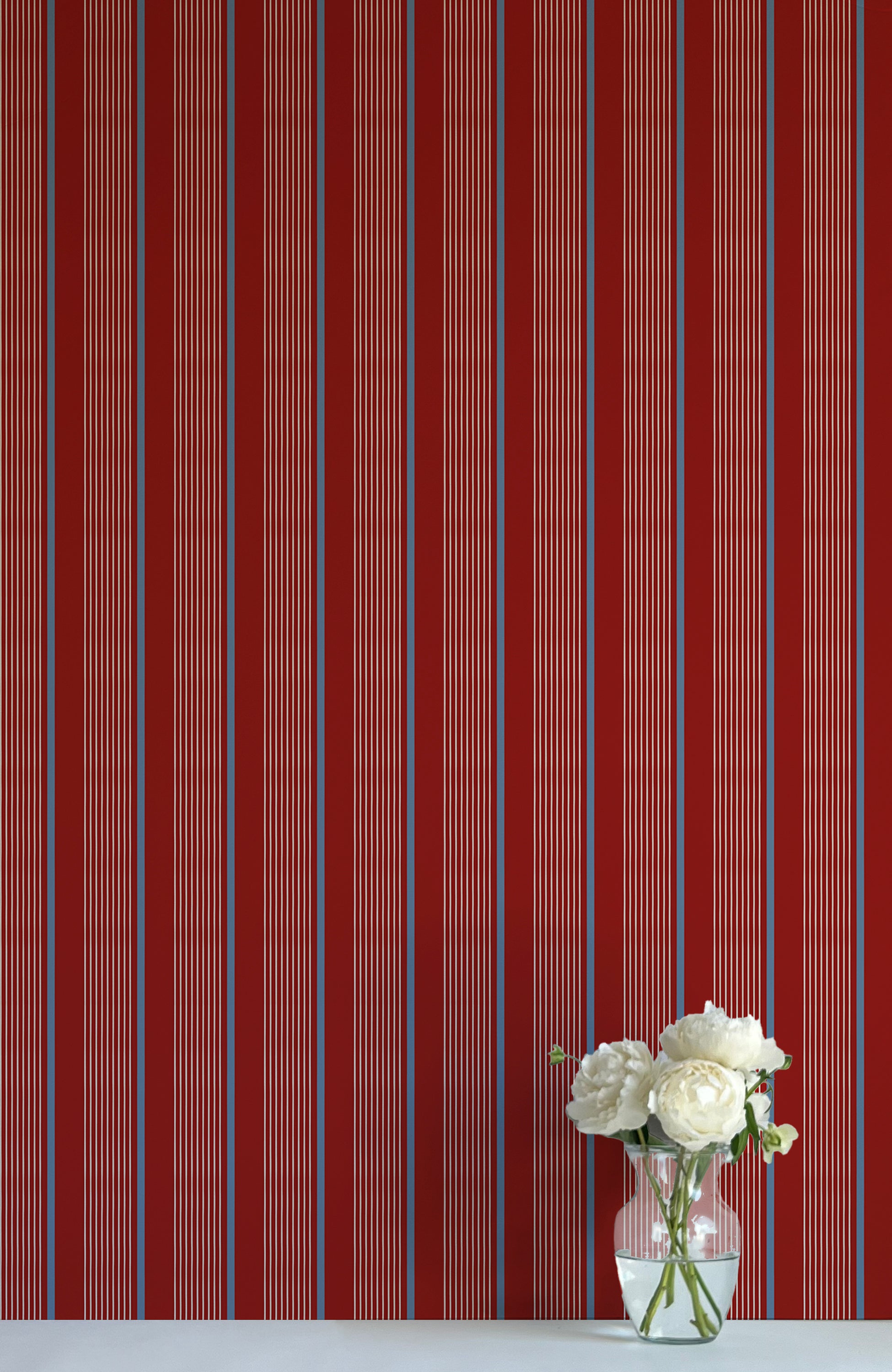 Striped red and blue wallpaper with a vase of flowers on a matching surface.