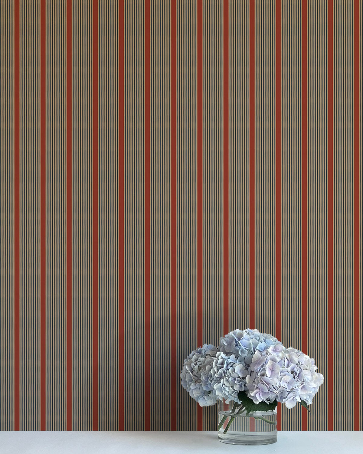 Striped wallpaper with a vase of flowers on a white surface