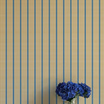 Striped wallpaper with a vase of blue flowers on a white surface