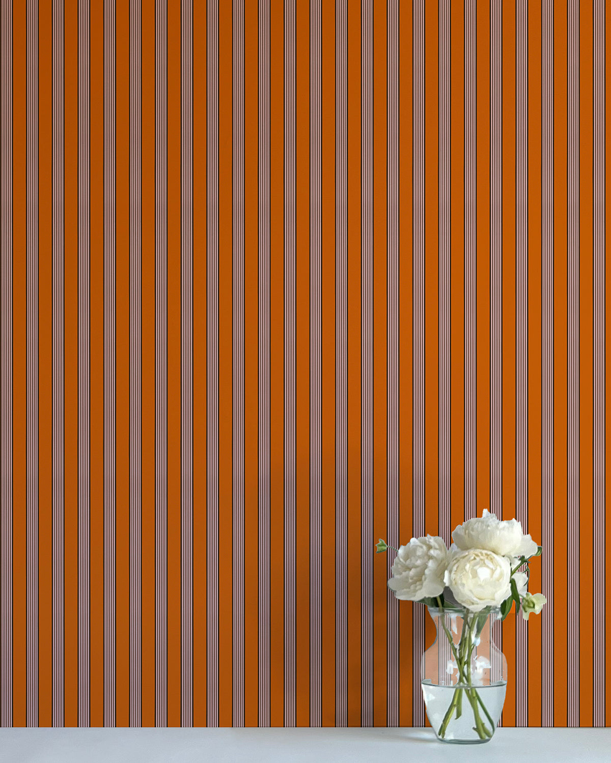 Striped wallpaper with a vase of flowers on a flat surface