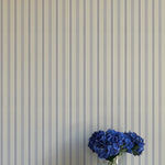 Striped wallpaper with a vase of blue flowers in the foreground