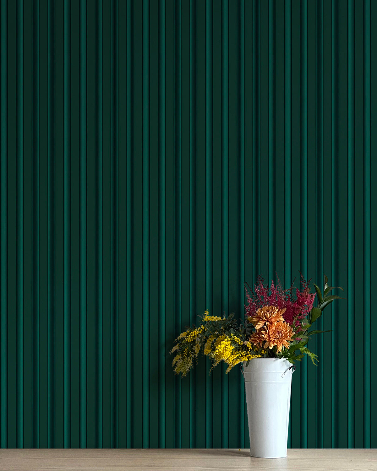 Potted plant with colorful flowers against a dark green striped wall.