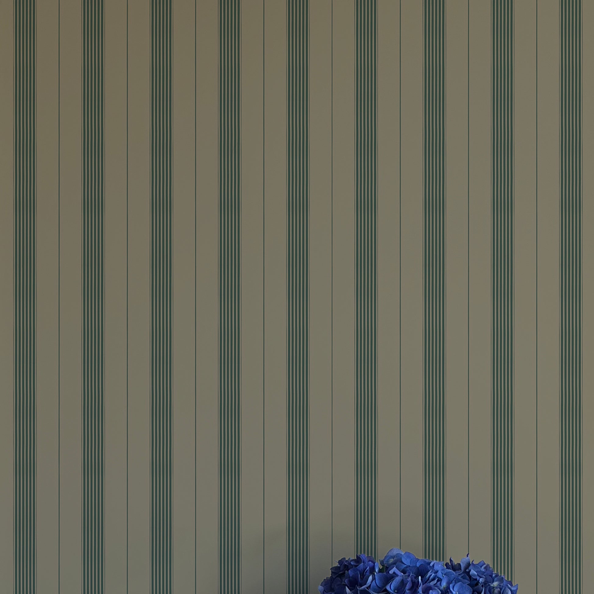 Striped wallpaper with a vase of blue flowers in the foreground