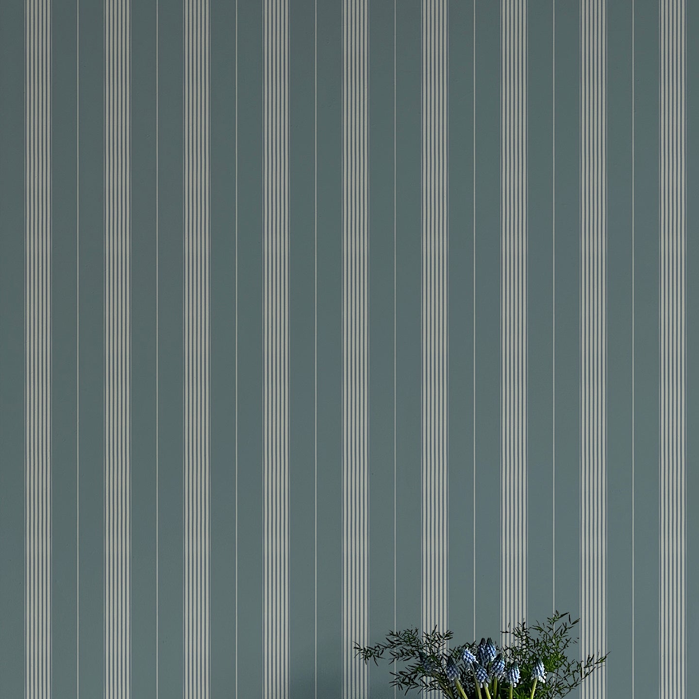 Striped wallpaper with a vase of flowers in the foreground