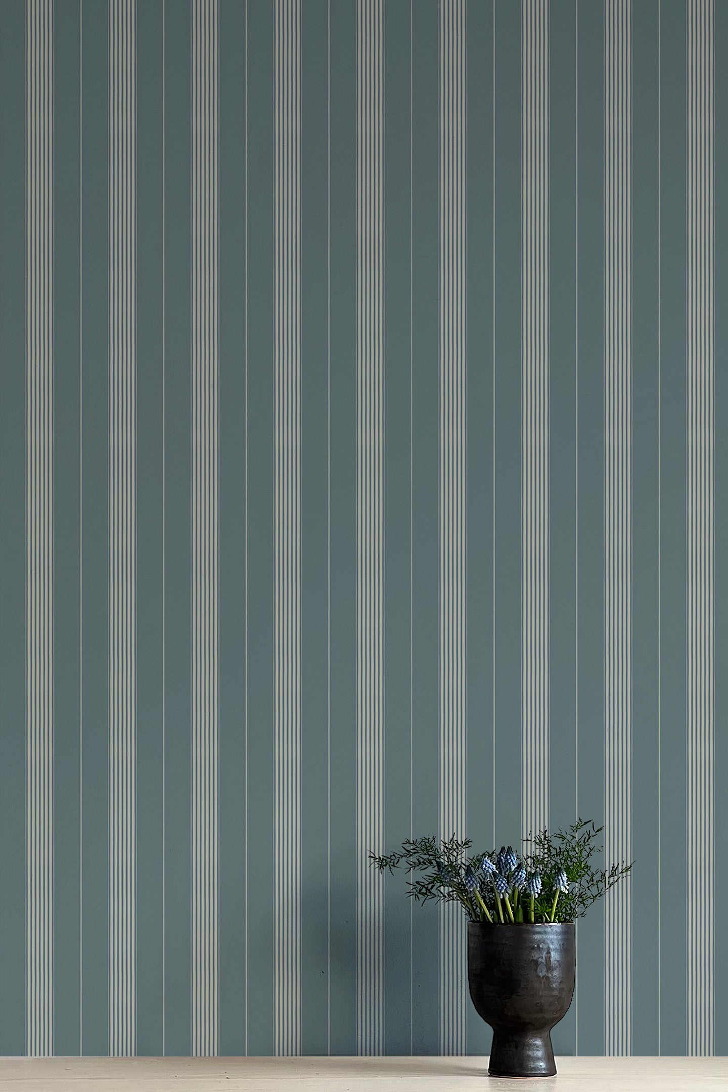 Striped wallpaper with a vase of flowers in the foreground