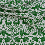 Draped patterned fabric with animals and sea creatures in green on a white background