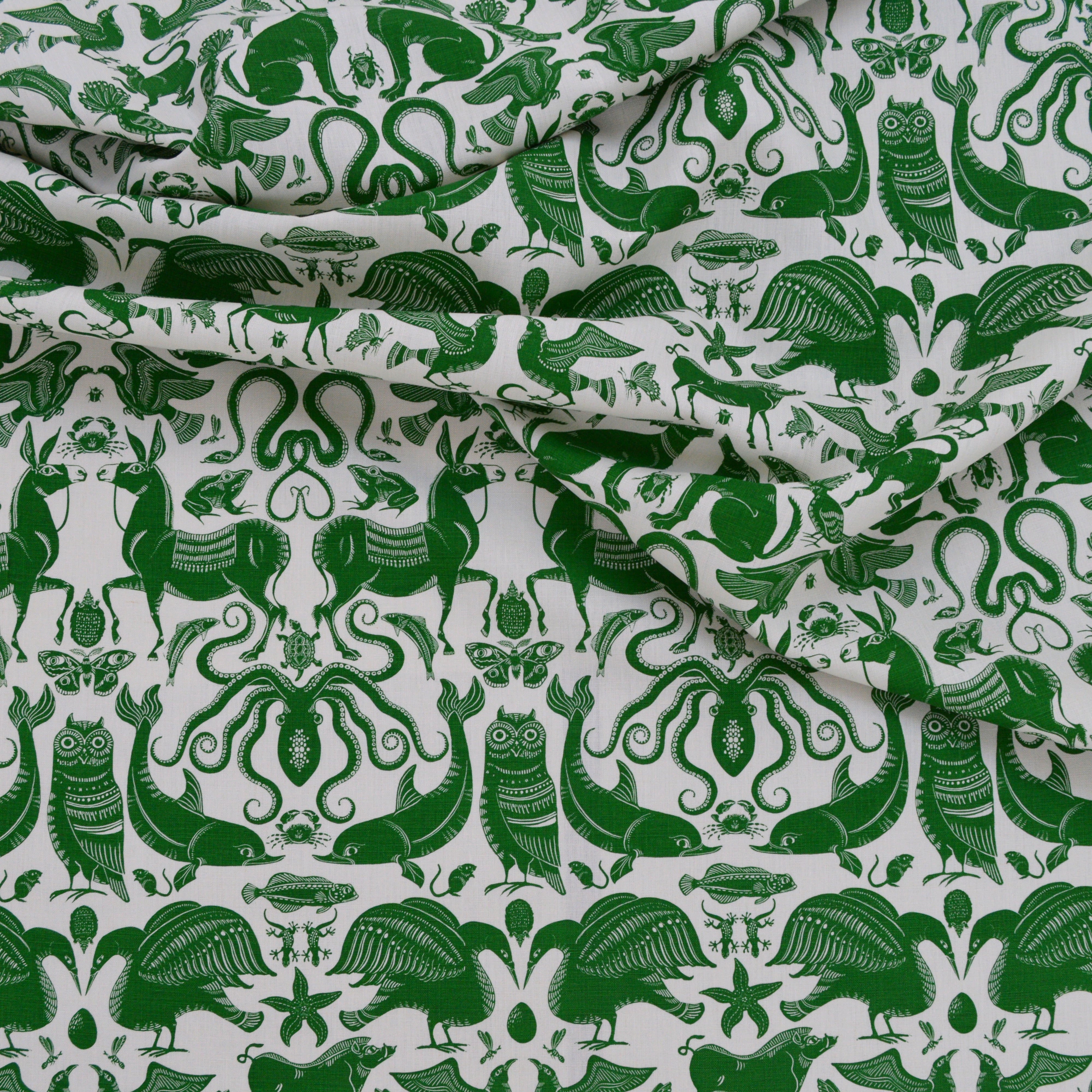 Draped patterned fabric with animals and sea creatures in green on a white background