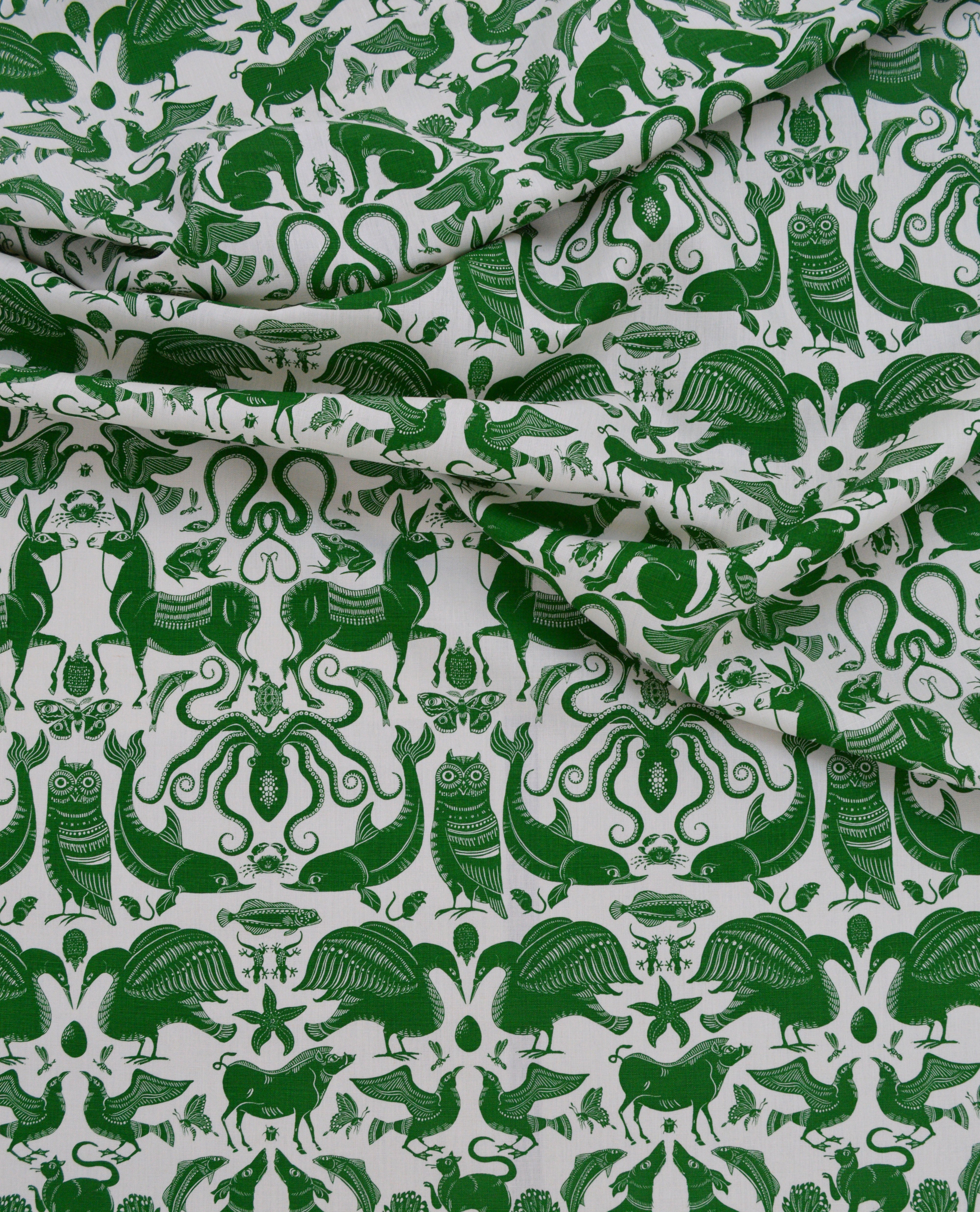Draped patterned fabric with animals and sea creatures in green on a white background