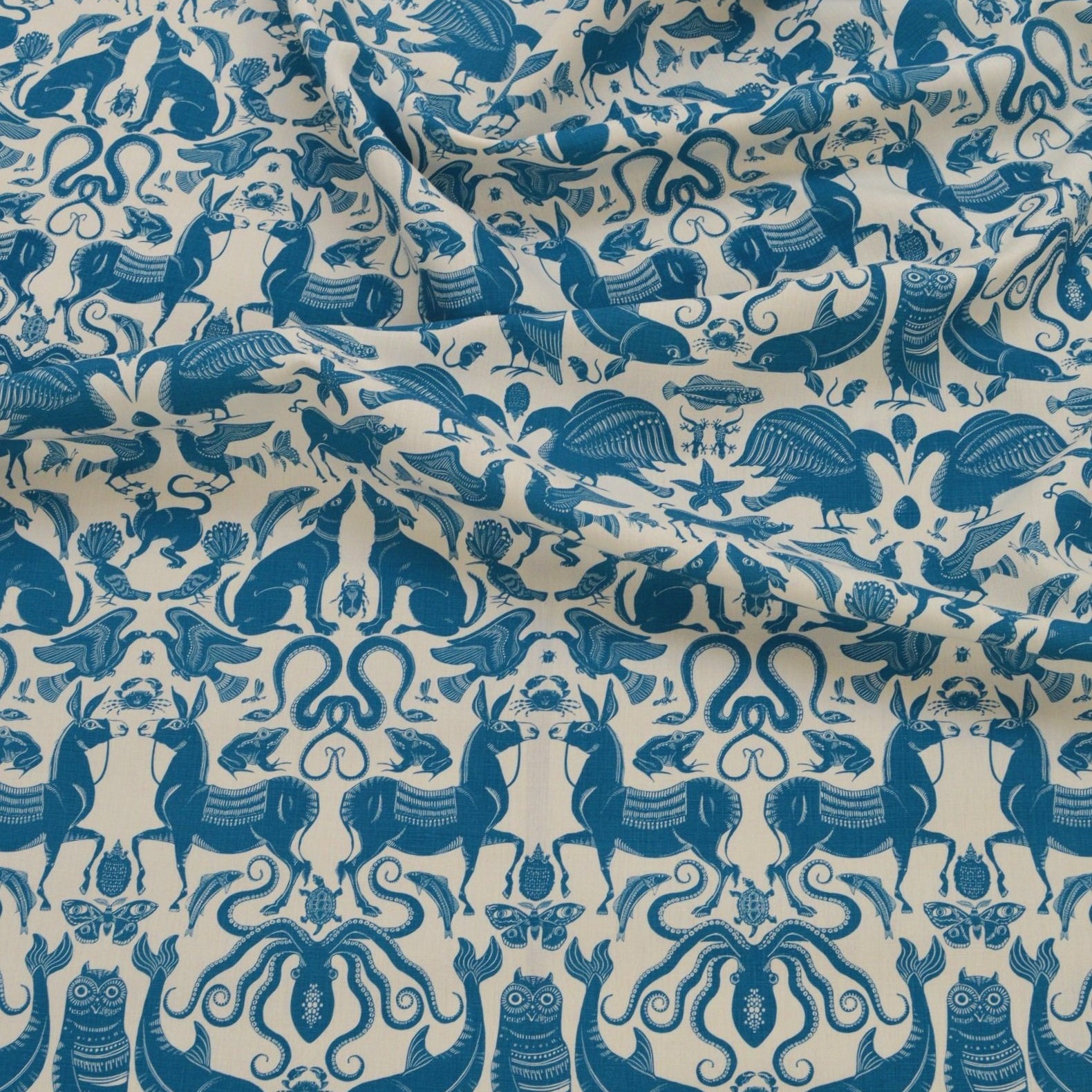 Draped patterned fabric with animals and sea creatures in blue on a white background