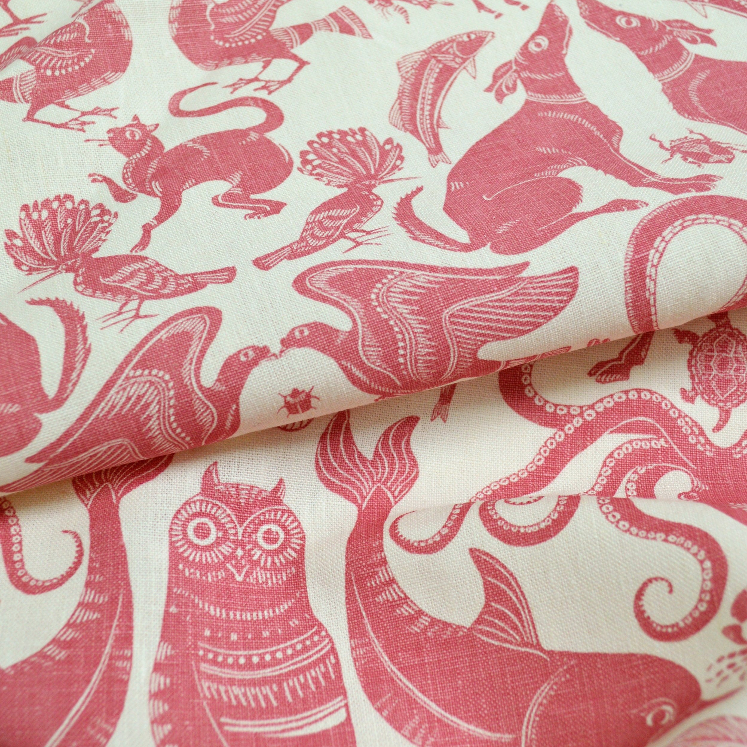 Draped patterned fabric with animals and sea creatures in pink on a white background