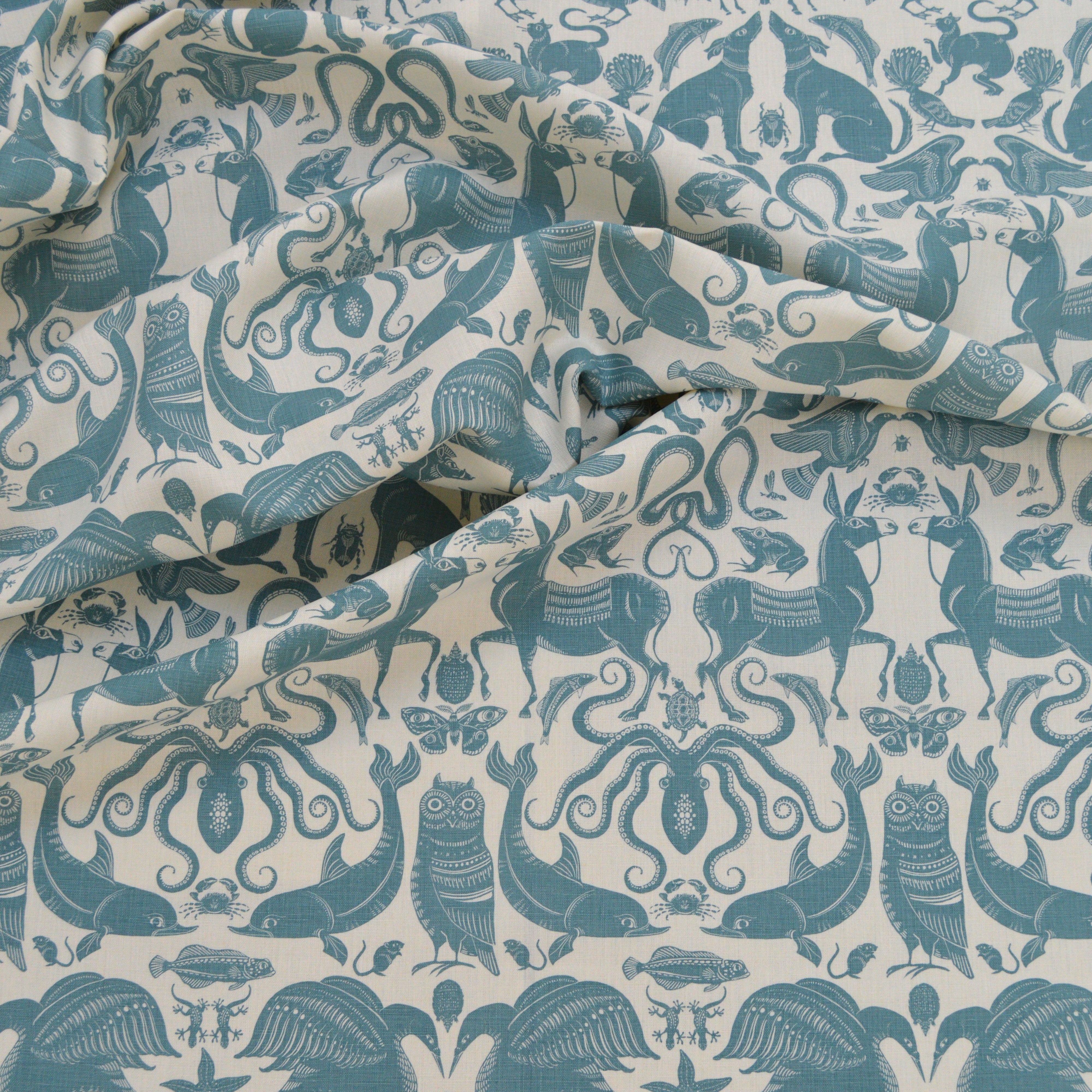 Draped patterned fabric with animals and sea creatures in light blue on a white background