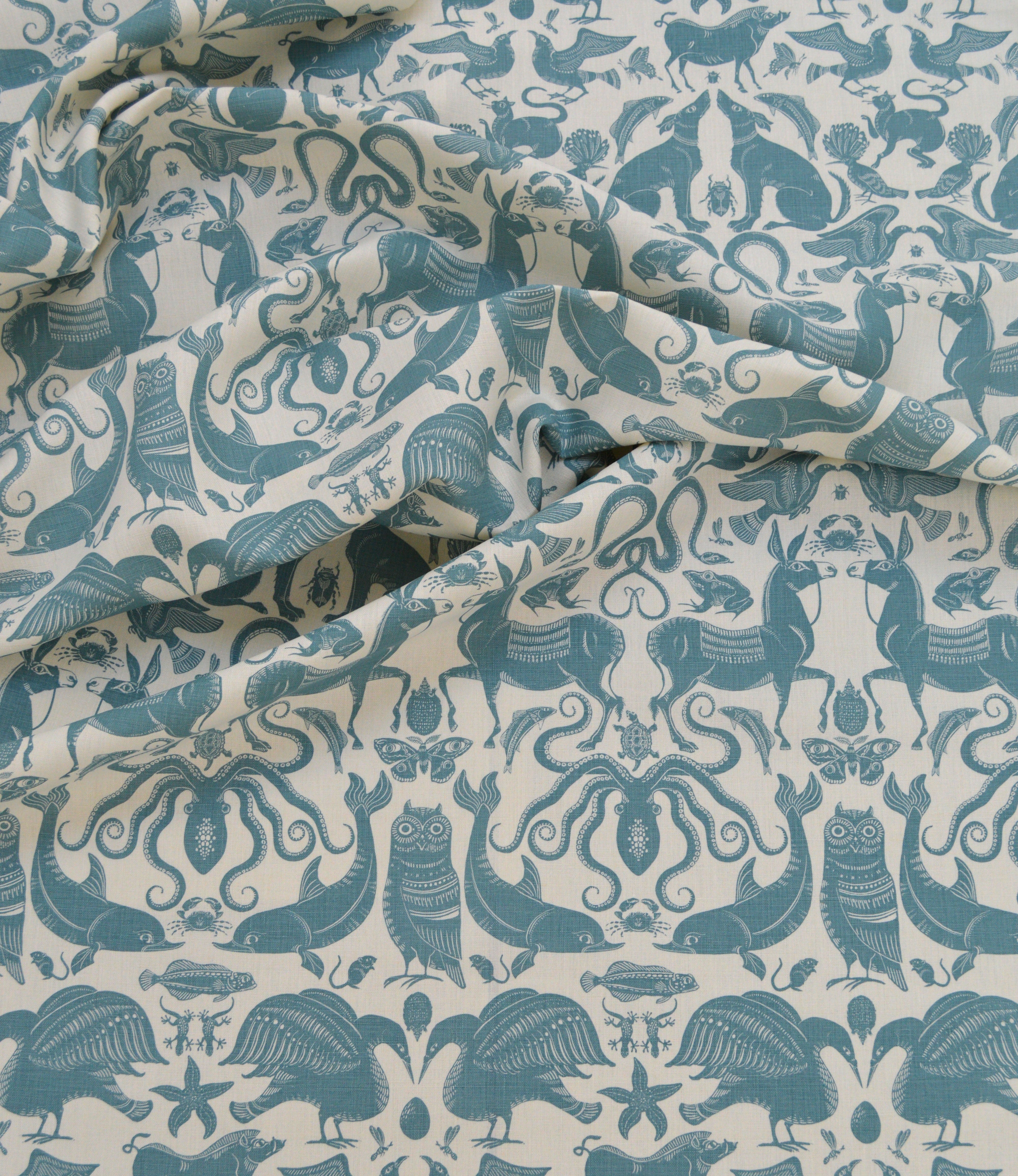 Draped patterned fabric with animals and sea creatures in light blue on a white background