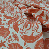 Draped patterned fabric with animals and sea creatures in orange on a white background
