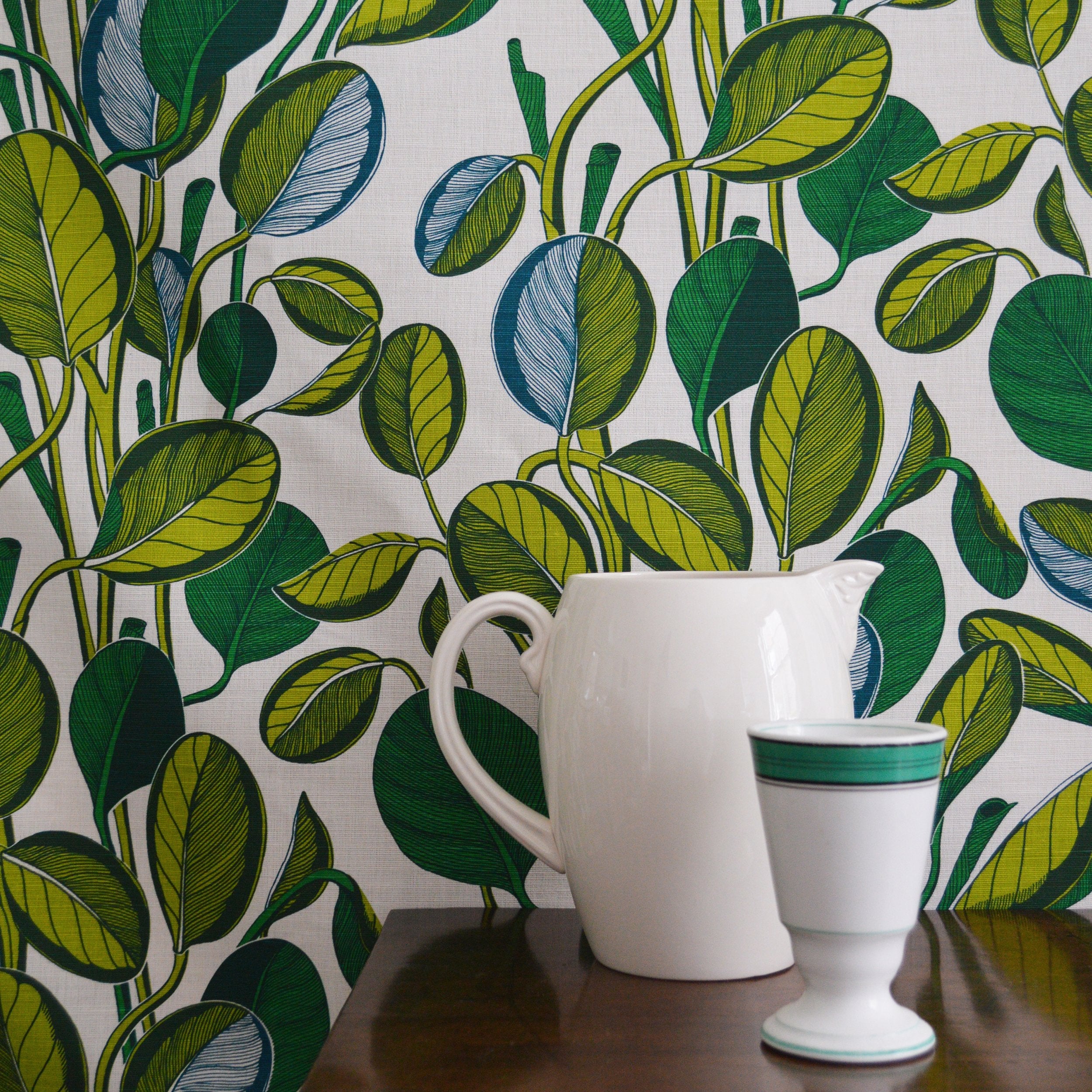 White pitcher and cup against a leaf-patterned fabric