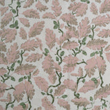 Patterned fabric with pink leaves and green acorns on a light background