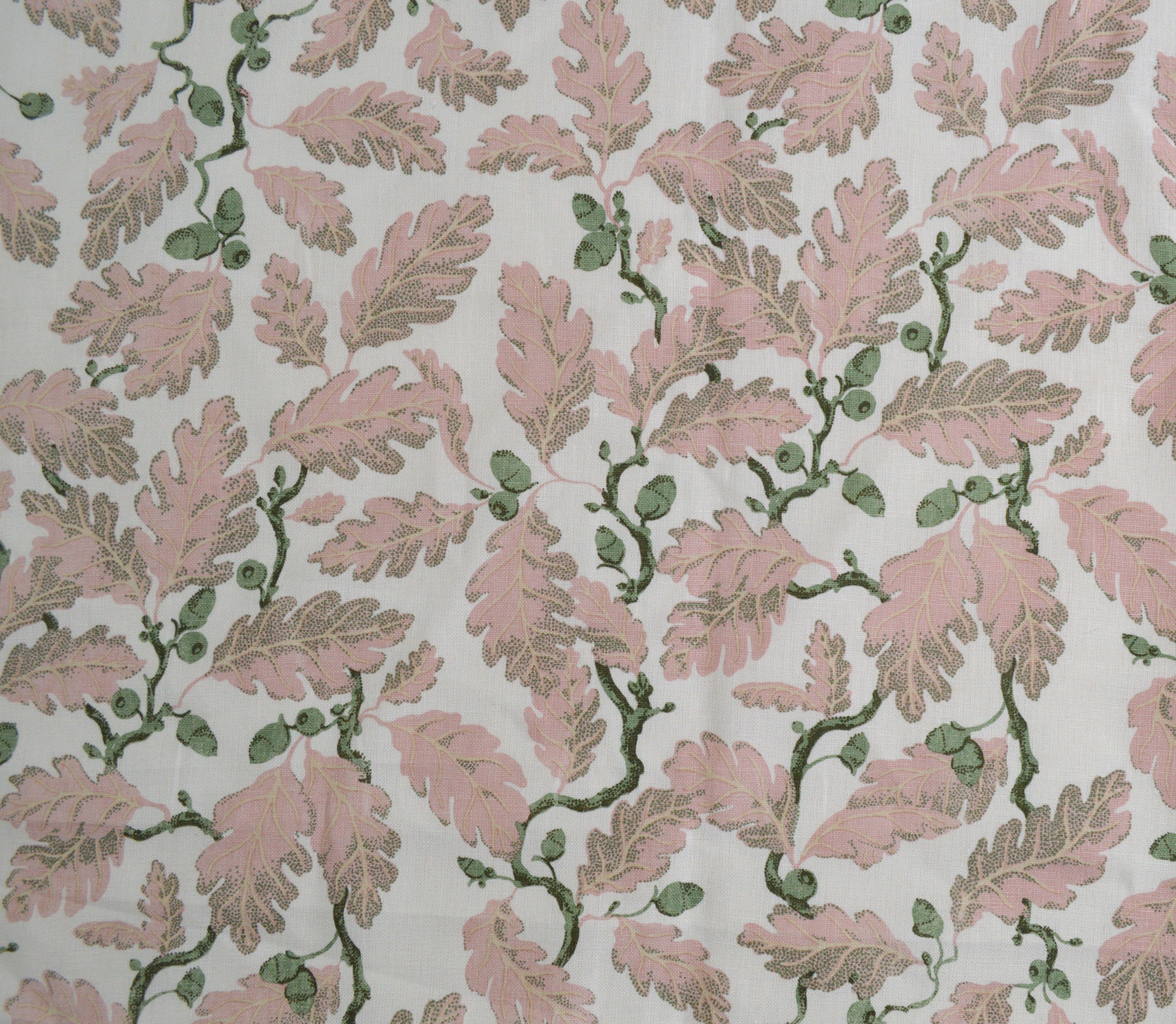 Patterned fabric with pink leaves and green acorns on a light background