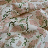 Botanical fabric with pink and green pattern on a white background