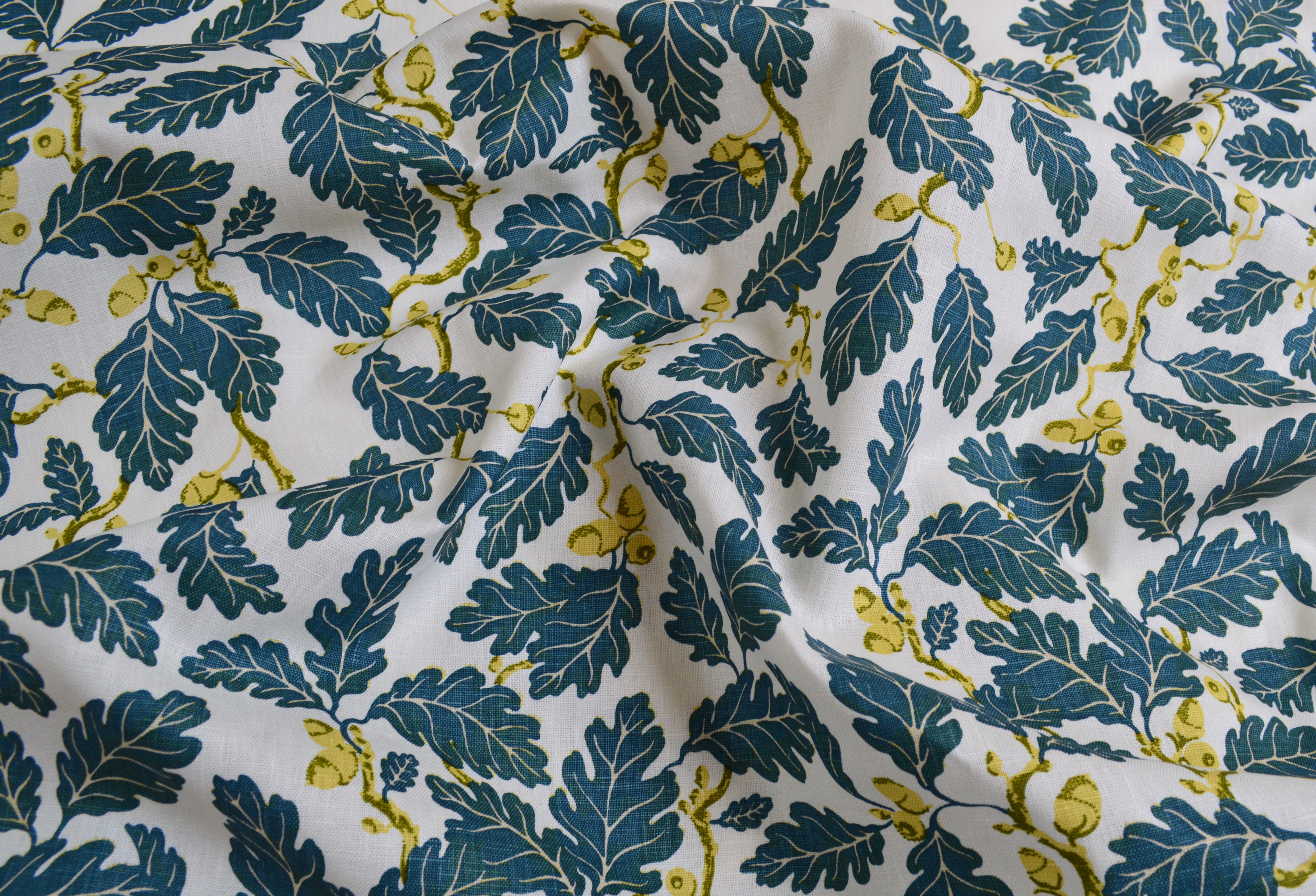 Fabric with blue leaf and yellow acorn pattern on a white background