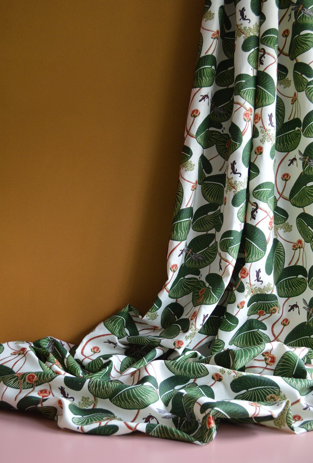 Fabric with green leaf pattern draped against a brown background