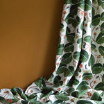 Fabric with green leaf pattern draped against a brown background