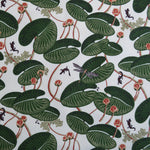 Patterned fabric with green lily pads, red flowers and small creatures on a white background