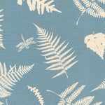 Detail of fabric in a repeating fern and dragonfly print in cream on a blue field.