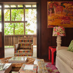 Cozy living space with wood-paneled walls, a large window, and an armchair upholstered in a geometric grid print.