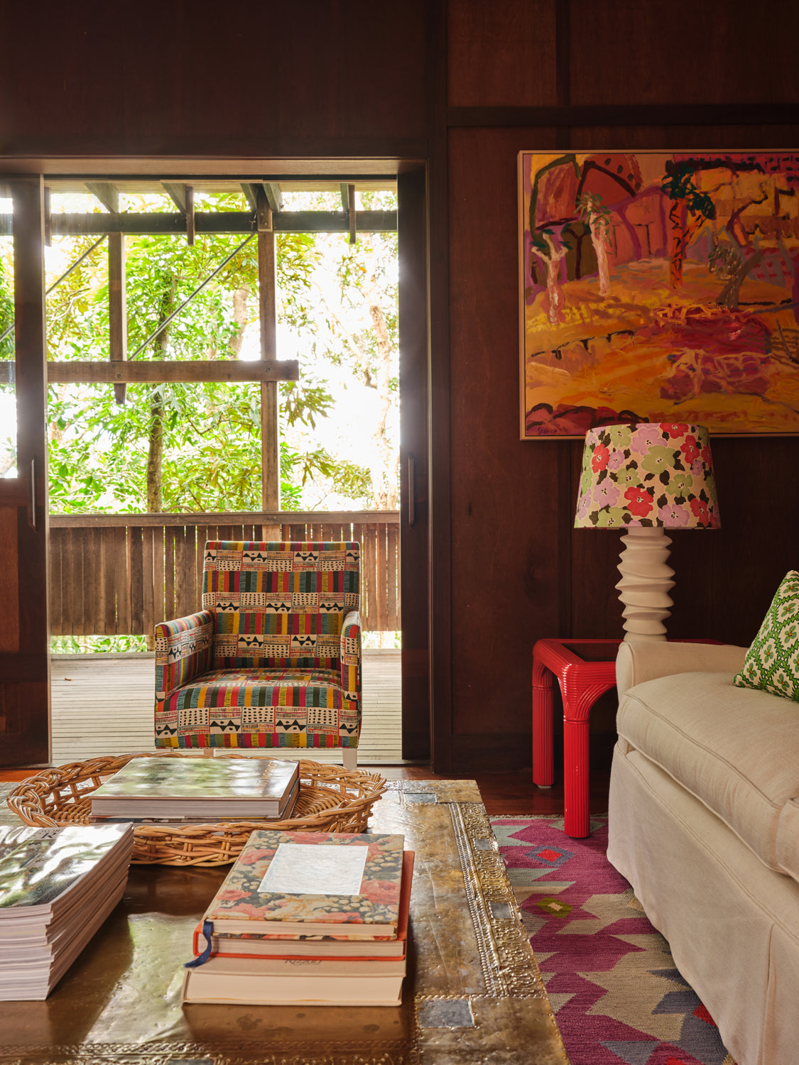 Cozy living space with wood-paneled walls, a large window, and an armchair upholstered in a geometric grid print.