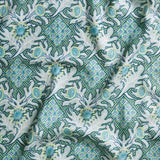 Draped fabric in a dense print mixing geometric and botanical motifs in turquoise, yellow and light aqua