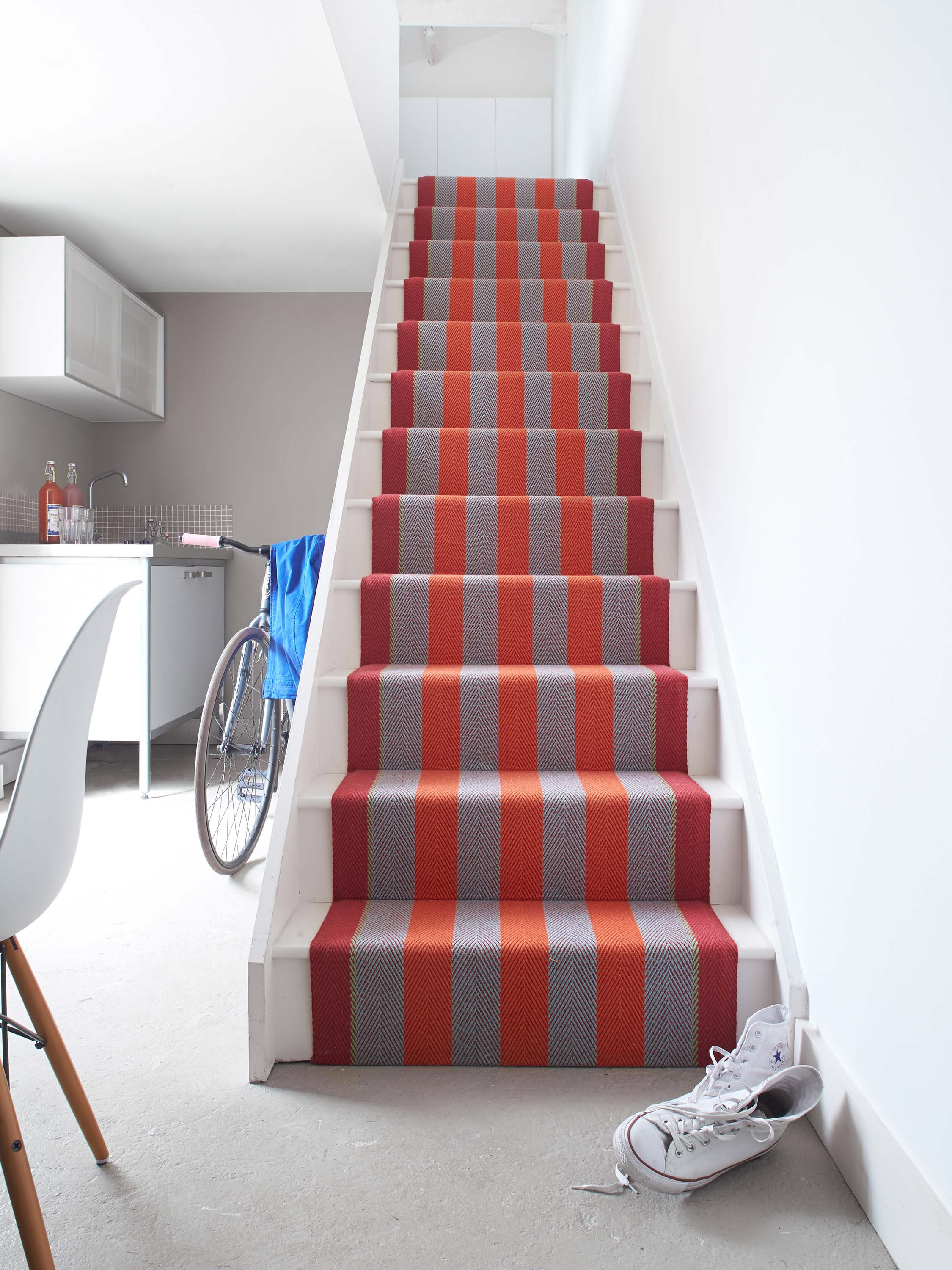 Striped flatweave runner in red and orange on white staircase