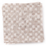 A stack of fabric swatches in a painterly checked pattern in shades of cream.