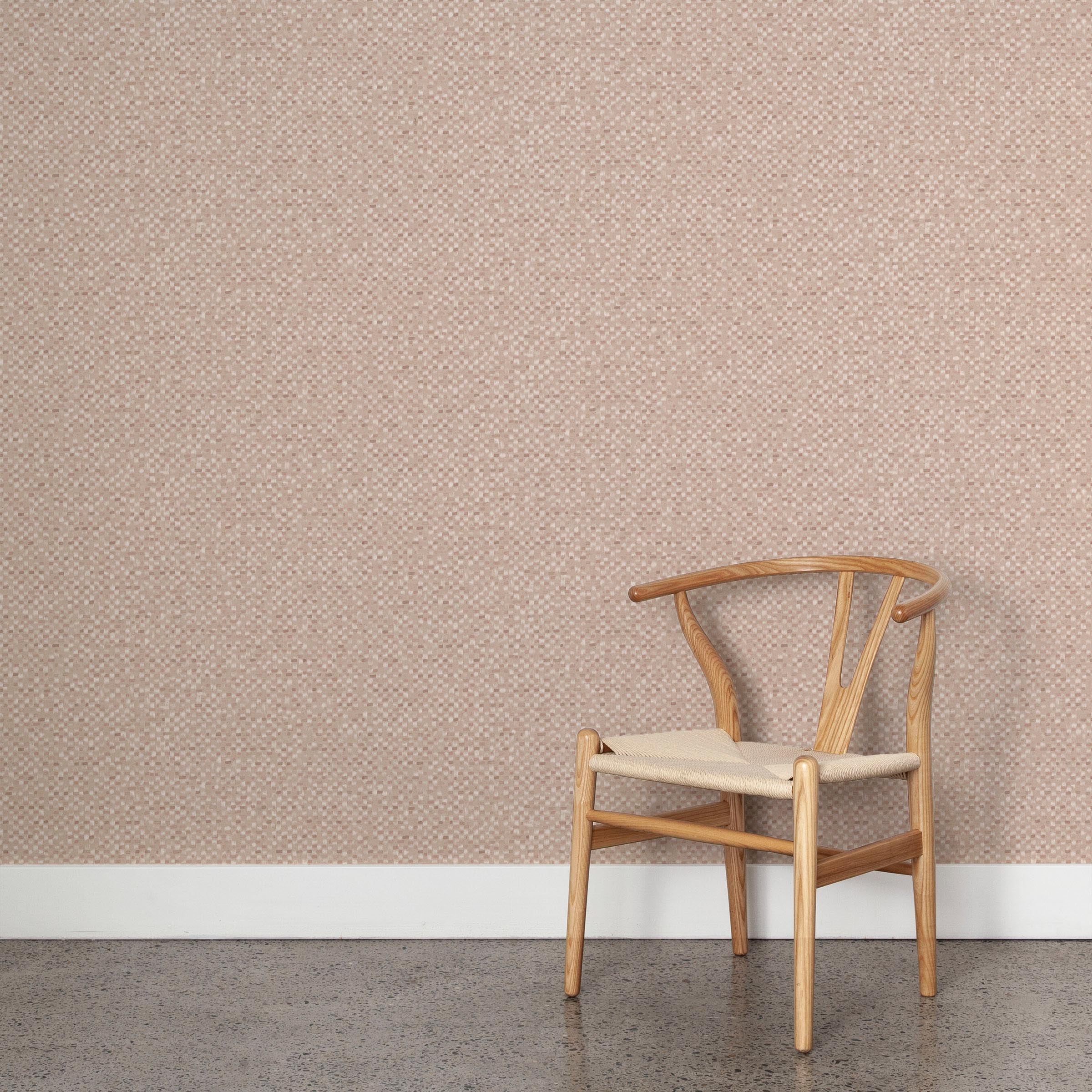 A wooden chair stands in front of a wall papered in a painterly checked pattern in shades of rust