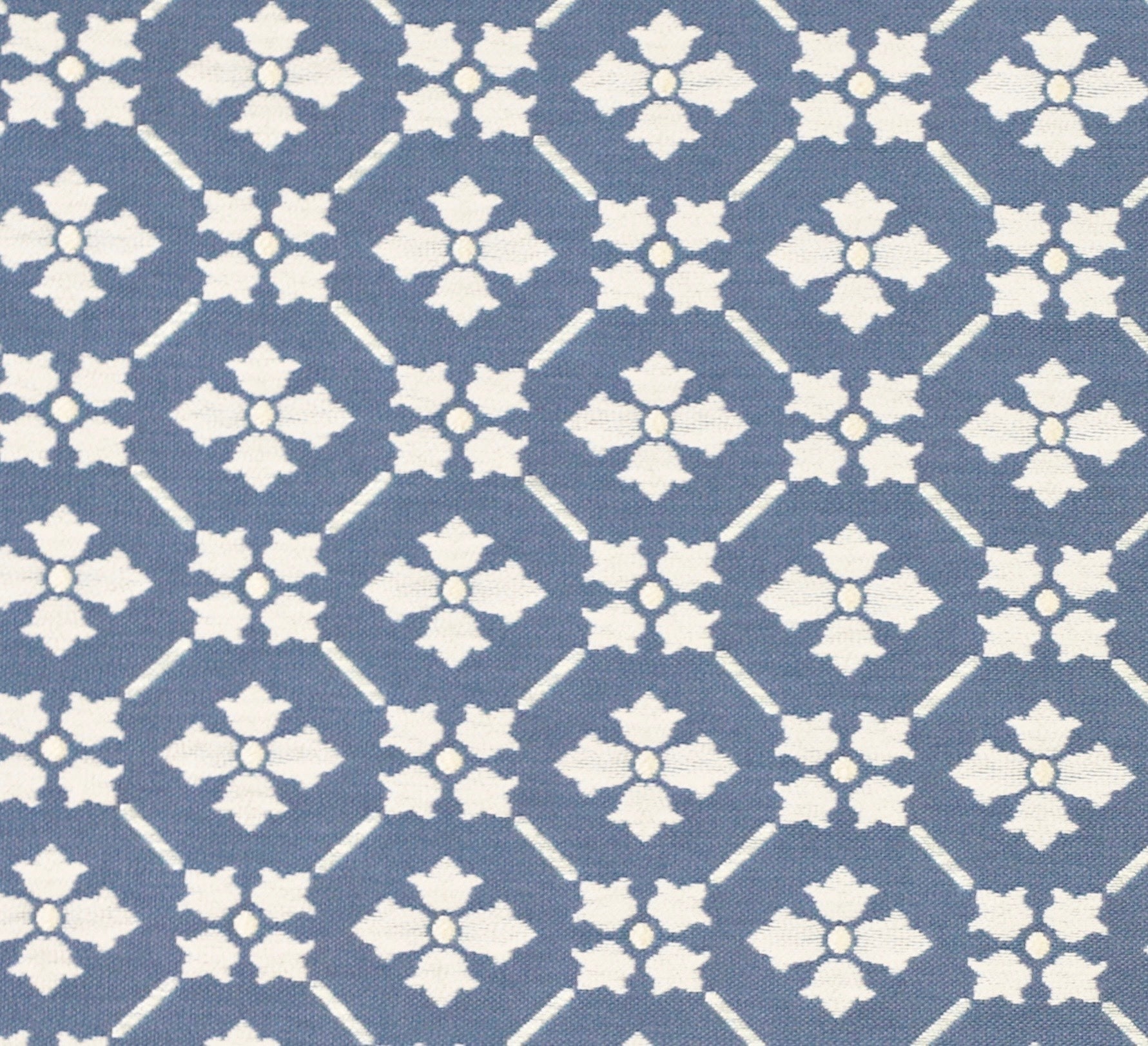 Detail of fabric in a repeating floral lattice print in cream on a blue field.