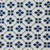 Detail of fabric in a repeating floral lattice print in blue and gold on a cream field.