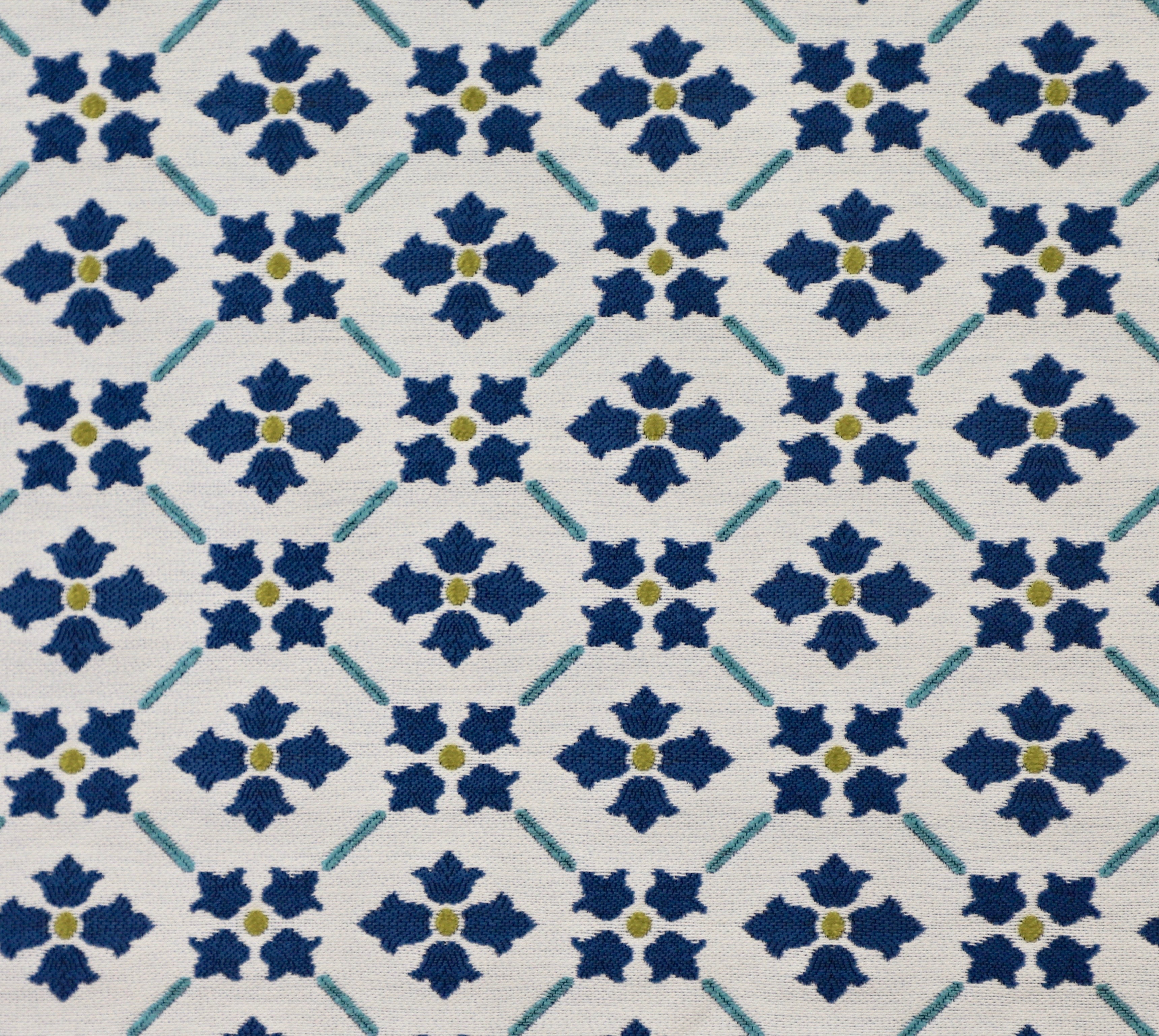 Detail of fabric in a repeating floral lattice print in blue and gold on a cream field.