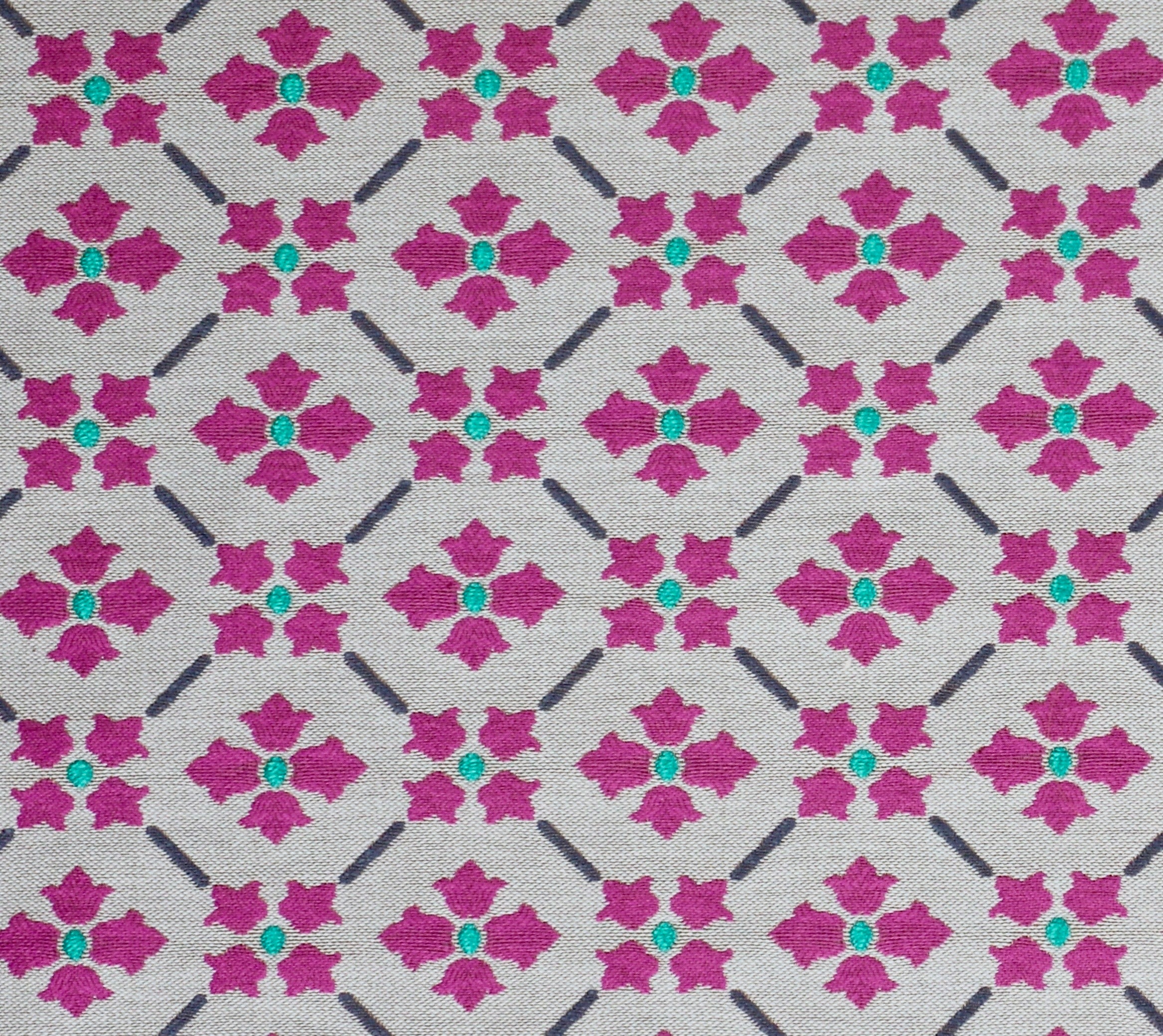 Detail of fabric in a repeating floral lattice print in magenta and turquoise on a greige field.