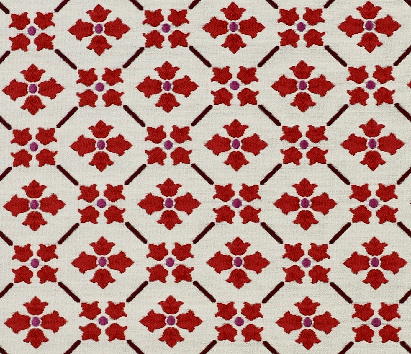 Detail of fabric in a repeating floral lattice print in red and brown on a cream field.