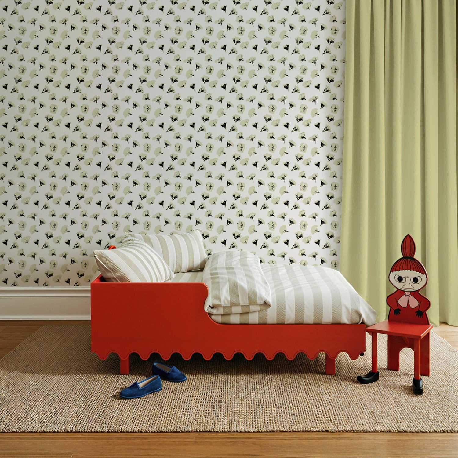 Red children's bed with striped bedding against a black and white floral patterned wall.