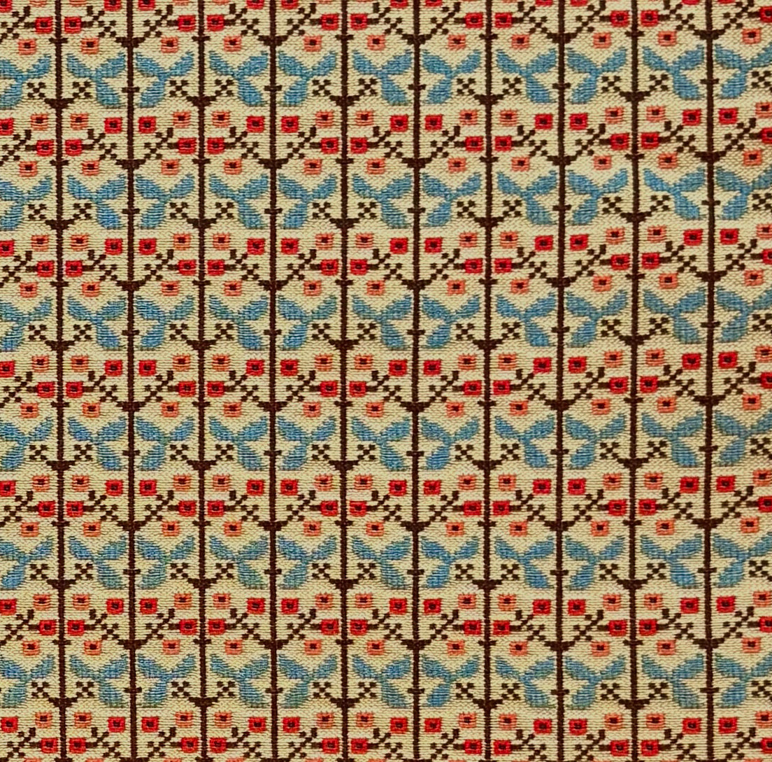 Patterned fabric with a gridded floral design in blue, orange and brown. 