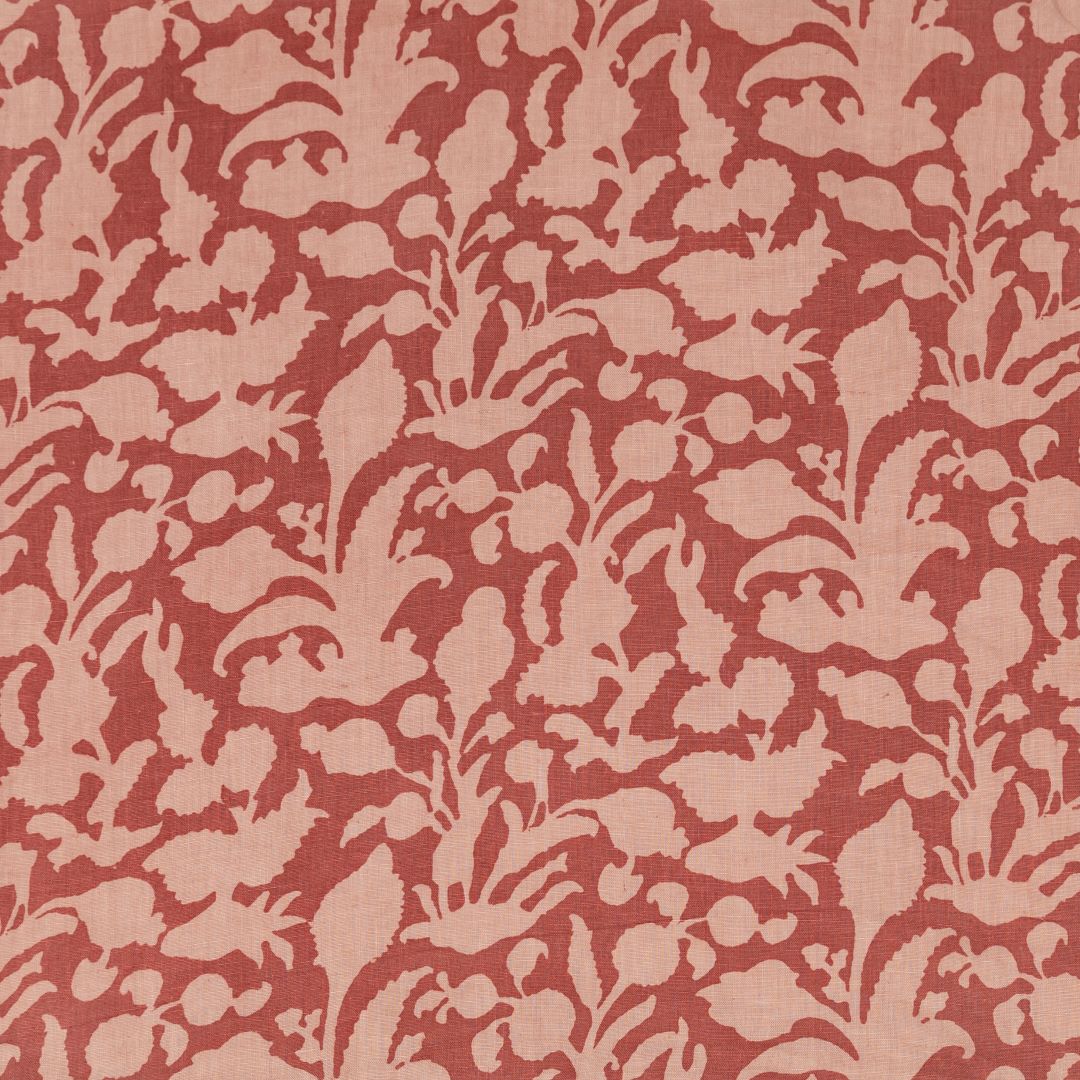 Detail of fabric in an abstract botanical print in ligth orange on a red field.