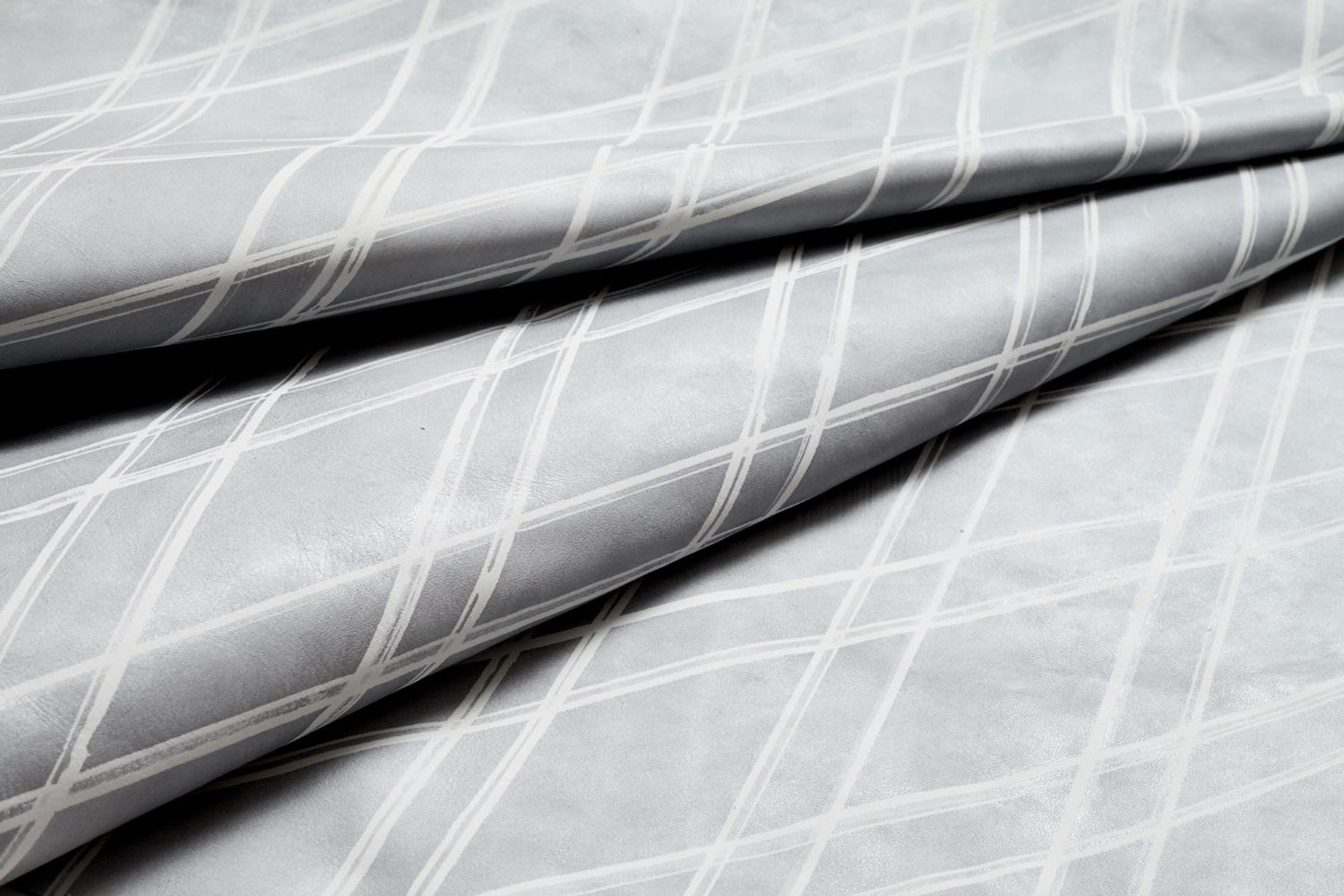 Close-up of a draped cowhide rug in light gray with a white lattice overlay.