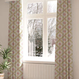 A large, sunny window with long curtains in a flower and leaf lattice print on a white field.